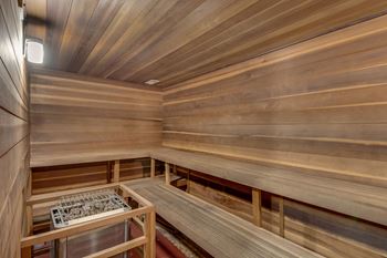 A wooden sauna with a bench and a container on the table.